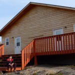 Bing sitting on the steps of the log house with 4 cabins